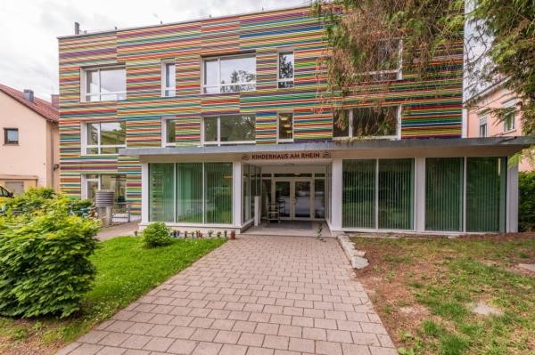 Eingang zu einem Kindergarten-Gebäude mit einer bunt gestreiften Fassade