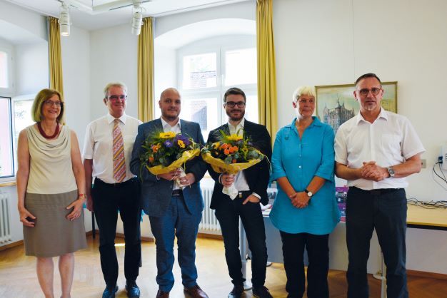 Eine Personengruppe - zwei Personen in der Mitte halten einen Blumenstrauß.