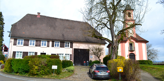 Bild Bagnatosteig 20, längliches Haus ( Hof) mit weiß-rosaner Kirche daneben