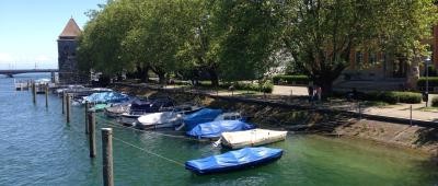 Bootsliegeplätze mit Booten am linksrheinischen Ufer des Seerheins. Im Hintergrund sind der Pulverturm und die alte Rheinbrücke zu sehen.