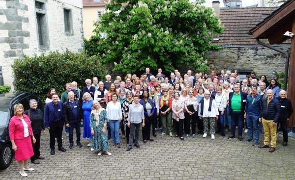 Eine große Gruppe Menschen steht in einem Hof, das Bild wurde erhöht aufgenommen