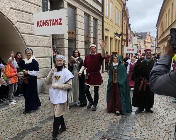 Personen laufen in mittelalterlichen Kostümen in einem Umzug, vorne trägt eine Person ein Schild mit "Konstanz".