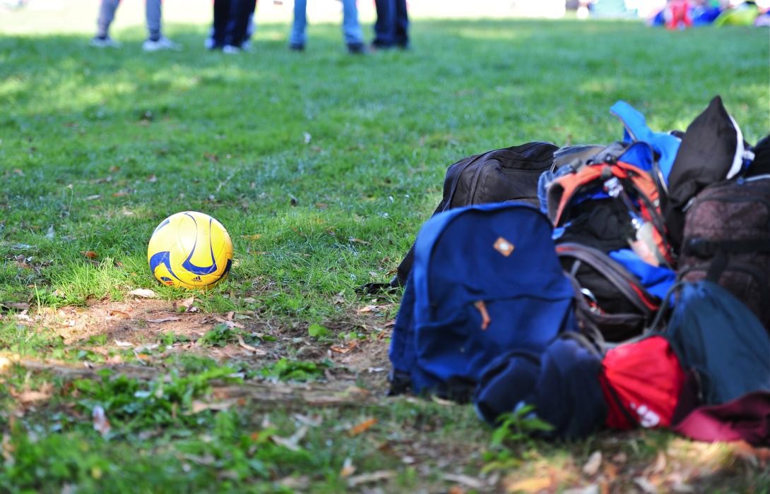 Ein Fußball und Rücksäcke auf einer Wiese