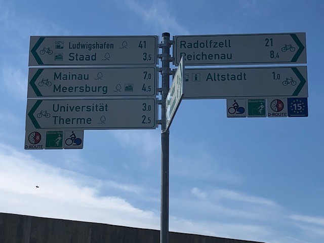 Ein Schild mit verschiedenen Radwegweisern, das in unterschiedliche Richtungen zeigt